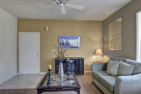 A living room with a couch, a coffee table, and a painting on the wall.