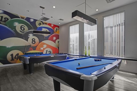 A pool table with a blue cloth and a wall with billiard balls.