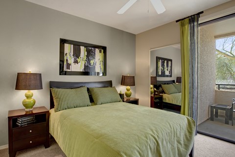 A bedroom with a bed, two lamps, and a painting on the wall.