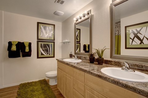 A bathroom with a toilet, two sinks, and a mirror.