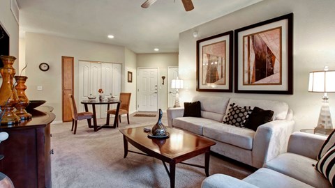 A living room with a white couch, a wooden coffee table, and a ceiling fan.
