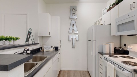 A kitchen with white cabinets and a black countertop.