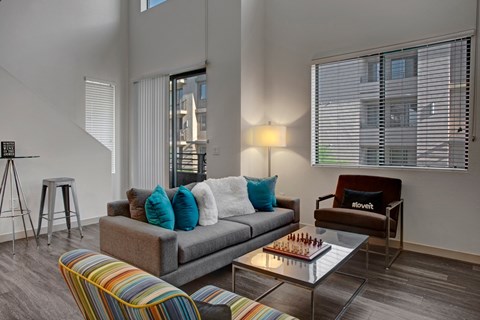 A living room with a grey couch and a glass coffee table.