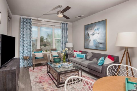 A living room with a grey couch, a white chair, a wooden coffee table, and a painting on the wall.
