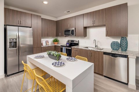 A modern kitchen with a white table and yellow chairs.