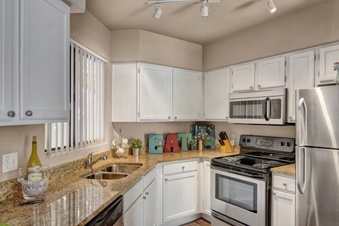 A kitchen with white cabinets and stainless steel appliances.