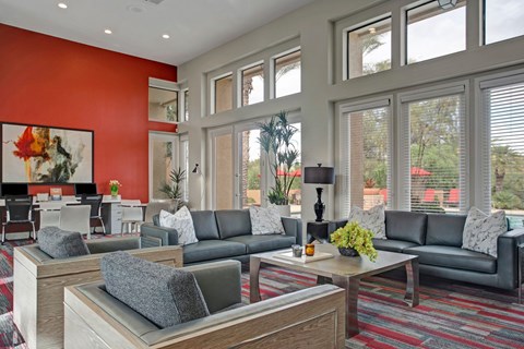 A living room with a grey couch and a red wall.
