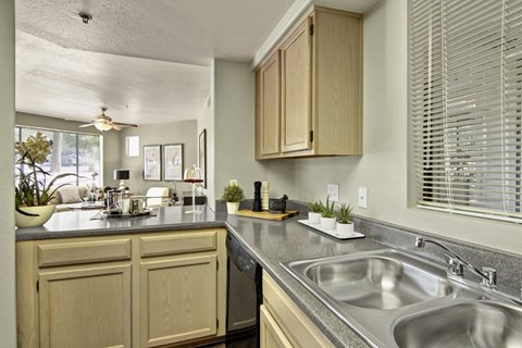 A kitchen with wooden cabinets and a black dishwasher.