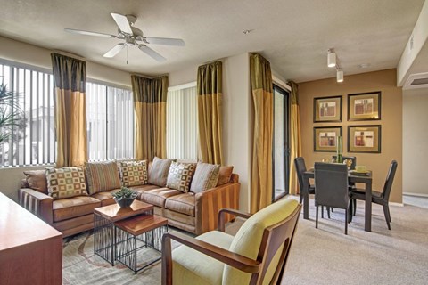 A living room with a brown sofa, a coffee table, and a dining table with chairs.
