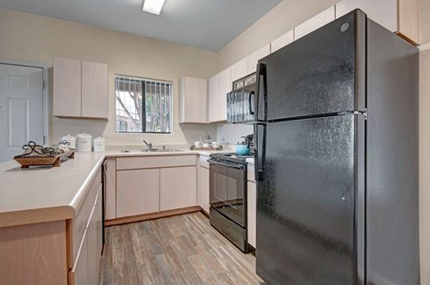 A kitchen with a black refrigerator and wooden cabinets.