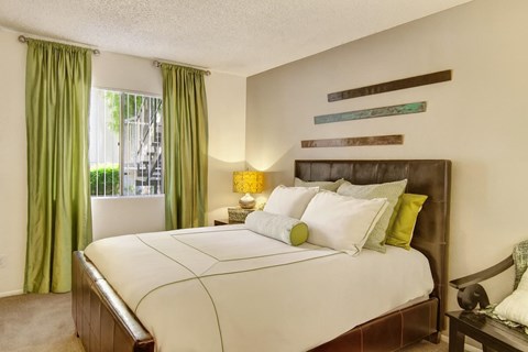 A bedroom with a large bed and green curtains.