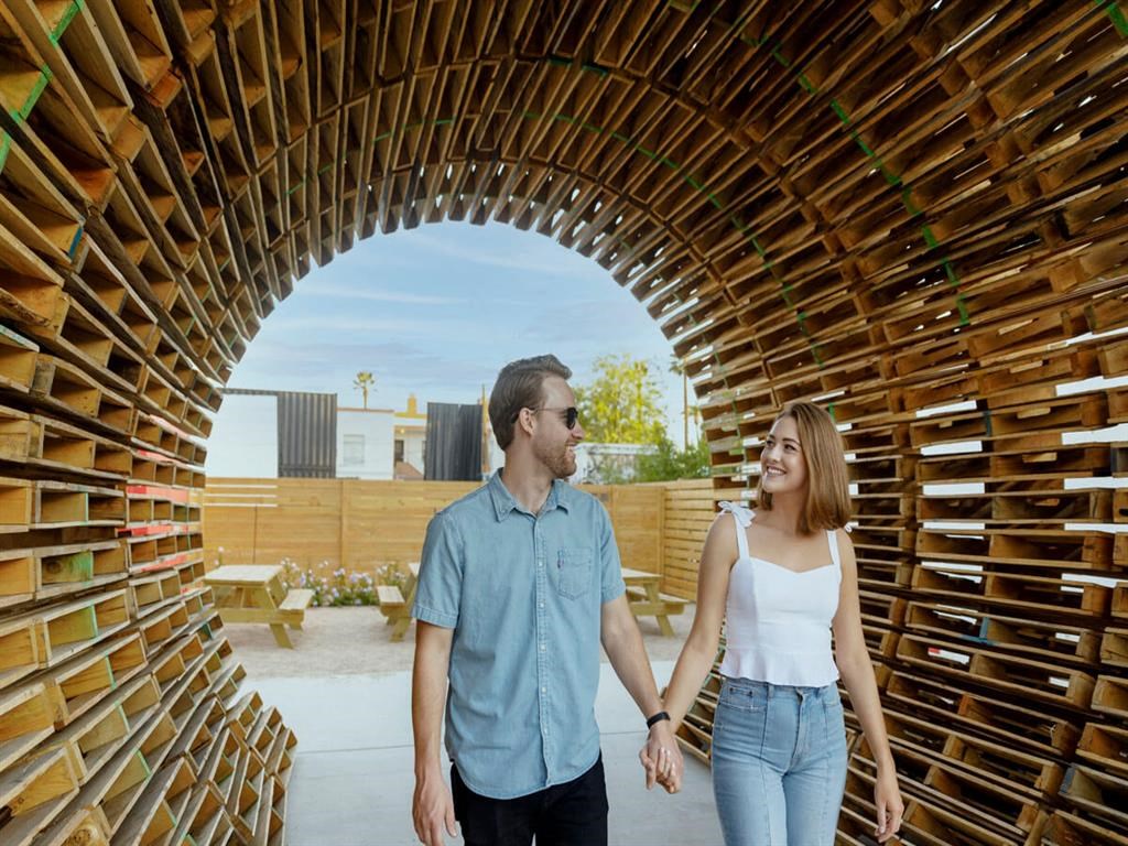 a couple holding hands and walking through a wooden tunnel
