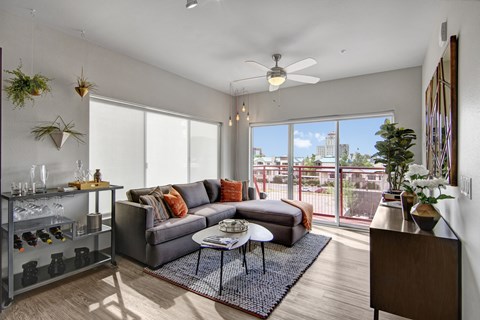 A living room with a grey couch and a glass table.