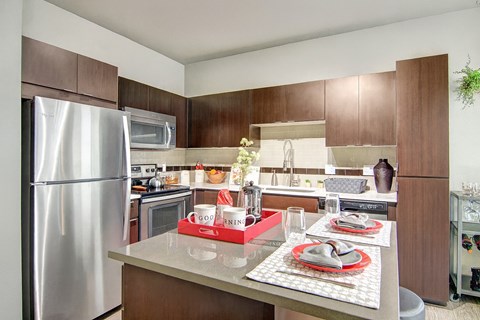 A modern kitchen with a stainless steel refrigerator and brown cabinets.