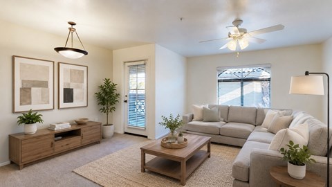 A living room with a grey couch, a wooden coffee table, and a ceiling fan.