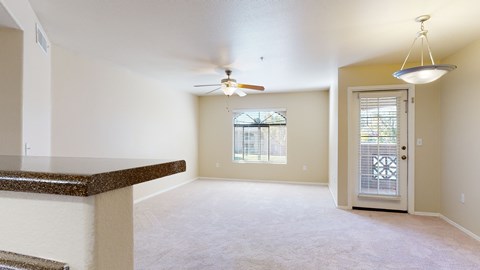 A spacious room with a ceiling fan and a door leading to a balcony.
