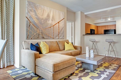 A living room with a couch, a coffee table, and a painting of a bridge.