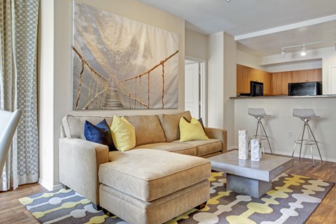 A living room with a couch, a coffee table, and a painting of a bridge.