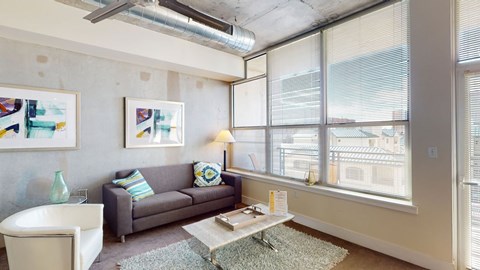 A living room with a grey couch, a white chair, a coffee table, and a painting on the wall.
