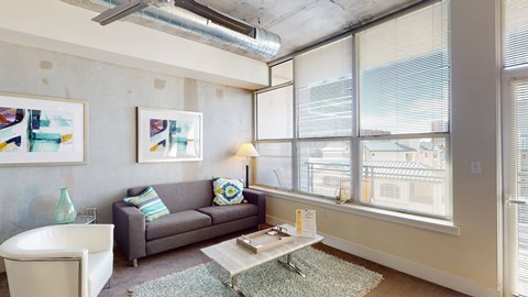 A living room with a grey couch, a white chair, a coffee table, and a painting on the wall.
