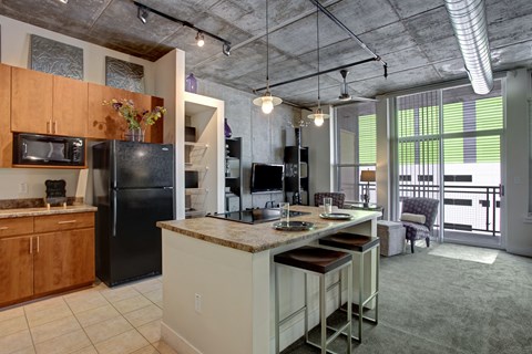 A kitchen with a black refrigerator and a black microwave.