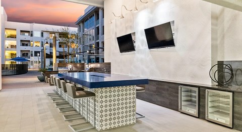 A modern kitchen with a long counter and chairs.