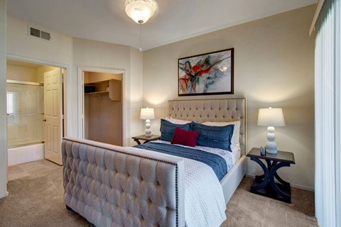 A bedroom with a large bed and a painting on the wall.