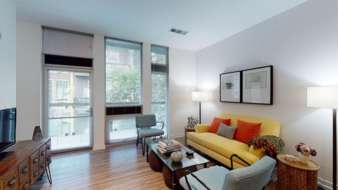 A living room with a yellow couch and a wooden coffee table.
