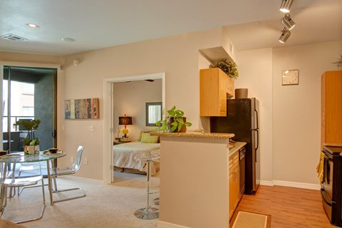 A kitchen with a refrigerator, sink, and a dining table with chairs.