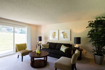 A living room with couches, chairs, and large sliding glass doors leading out to the lawn Andorra Living Room - Photo Gallery 5
