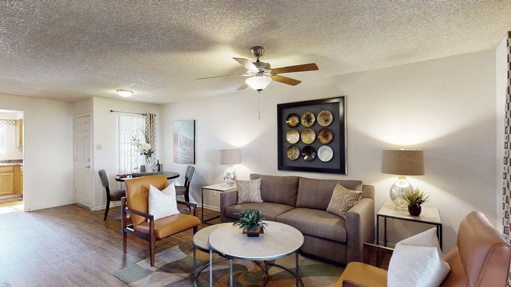 a living room with a couch table and chairs and a ceiling fan