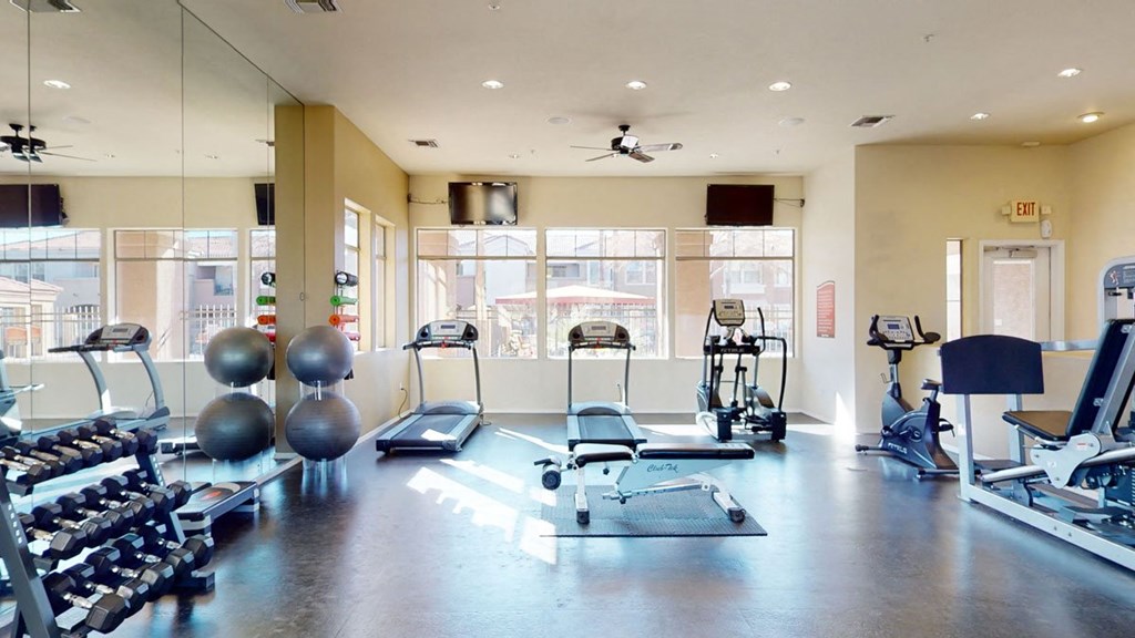 Spacious gym here at Dobson Towne Centre Apartments with treadmills, stationary bikes, free weights, and exercise balls. Sunlight pours through large windows, creating a bright, welcoming atmosphere.