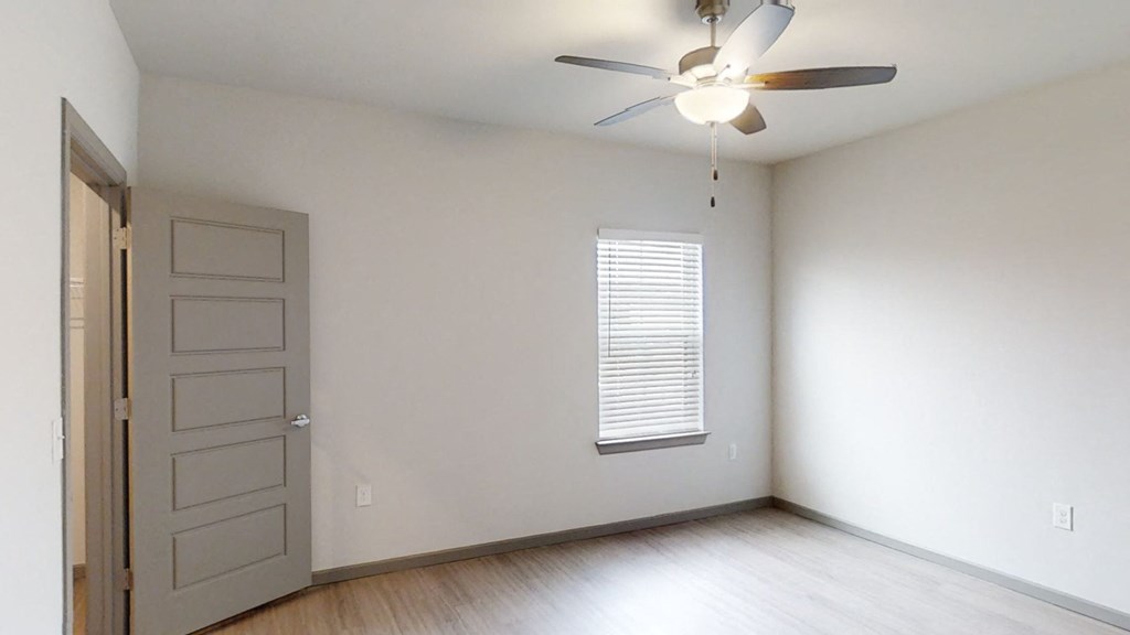 an empty living room with white walls and a ceiling fan