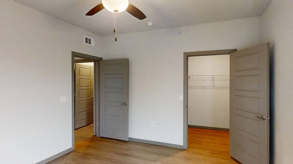 an empty room with two doors and a ceiling fan