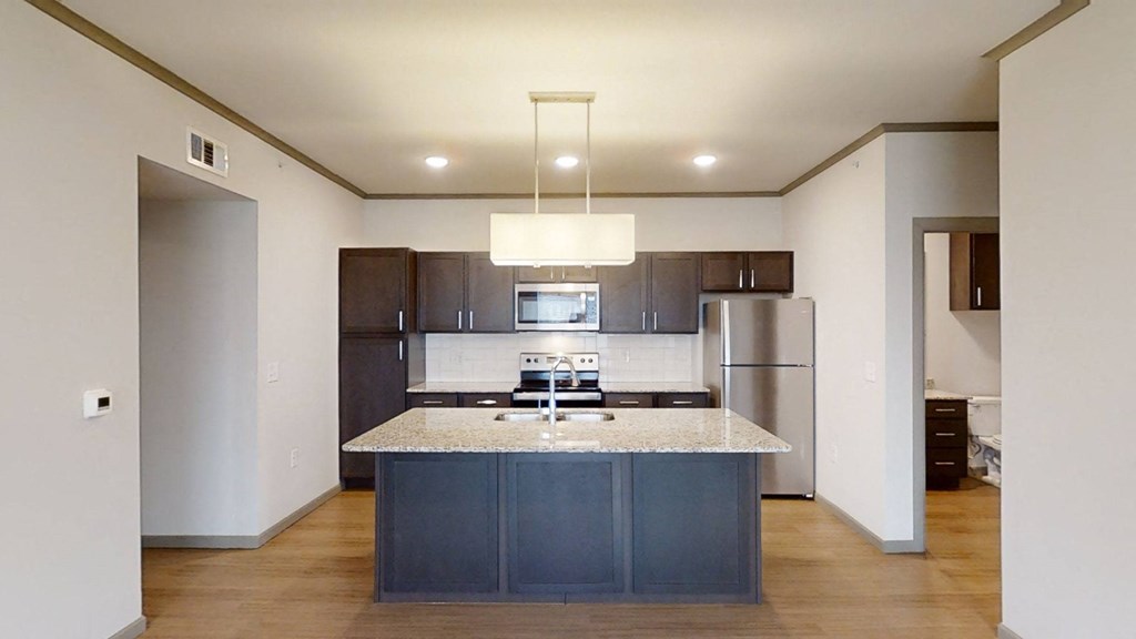 a kitchen with a marble counter top and a stainless steel refrigerator
