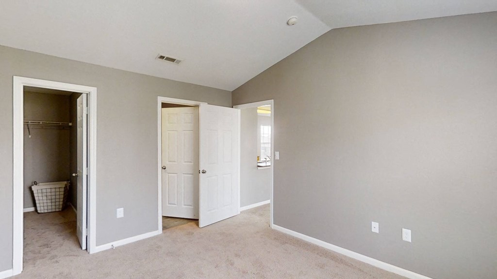 A bedroom with a closet and a door to a bathroom