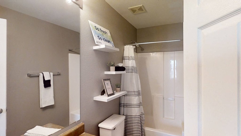 A bathroom with a shower and a towel rack and a toilet