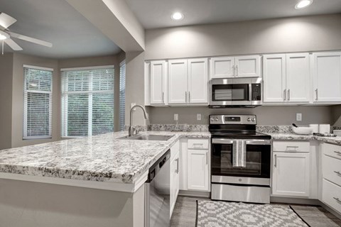 A kitchen with a granite countertop and stainless steel appliances.