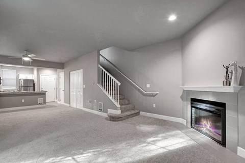 A living room with a fireplace and a staircase.