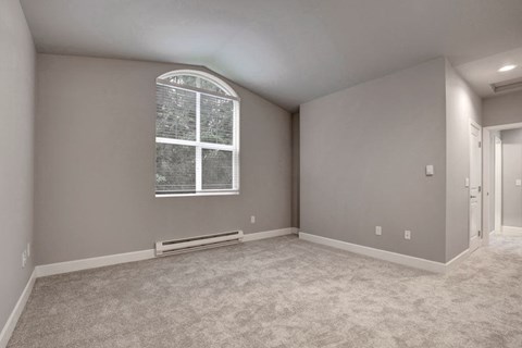 A room with a window and a carpeted floor.