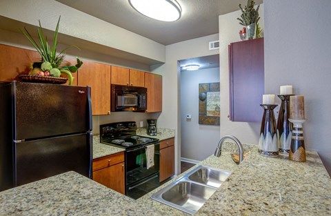 A kitchen with a granite counter top and a black refrigerator.