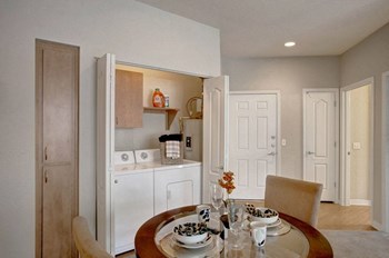 Bolero Apartments Living Room Living room view with dinner table, chairs. Opened closet showing washer and dryer in unit - Photo Gallery 4