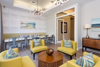 a living room with yellow furniture and a dining room with a table and chairs
