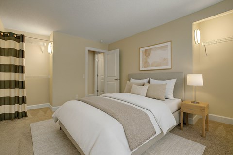 A bedroom with a large bed and a nightstand with a lamp.