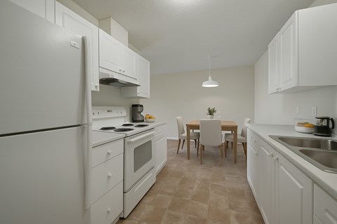A kitchen with white appliances and a table set for two.