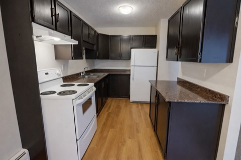 A kitchen with black cabinets and white appliances.