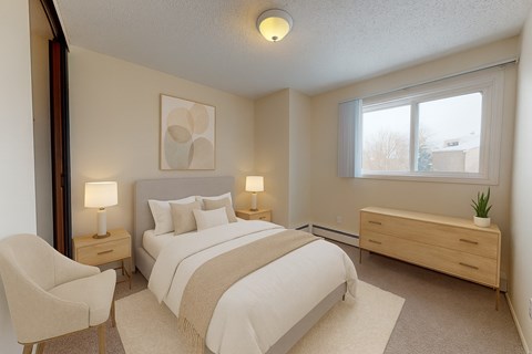 A bedroom with a large bed, a chair, and a nightstand with a lamp.