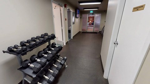 A convenient fitness area here at Cambridge West with a full set of free weights, rubber flooring, and bright overhead lighting, located near the community lounge for easy access.