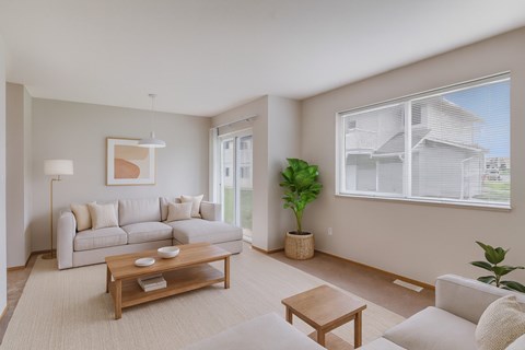A living room with a white couch, a wooden coffee table, and a large window.