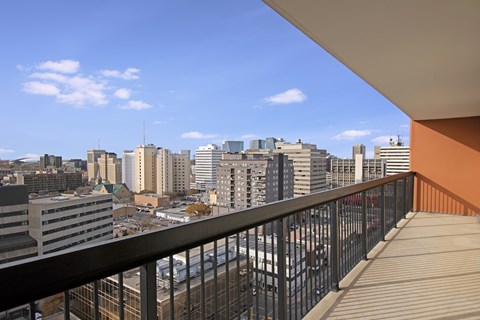 A sunny balcony here at Centre Pointe Plaza featuring a spacious outdoor layout with sturdy railing details, open-air cover for shade, and sweeping city skyline views under a bright blue sky for a refreshing, scenic escape.